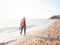 Girl wearing Blue jeans and red plaid shirt and backpacking yellow doing walking on the sea