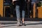 Girl wearing different shoes on her feet. Boots and sandals. Outdoor shot on a street