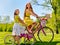 Girl wearing red polka dots dress rides bicycle into park.