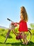 Girl wearing red polka dots dress rides bicycle into park.