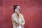 Girl wearing a reusable mask and talking on the phone with a red wall on the background