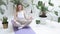 Girl wearing sportswear sits in lotus pose on mat, enjoys breathing practice