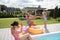 Girl wearing swimsuit splashing water on parents near pool