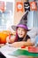 Girl wearing wizard Halloween costume laughing while drawing scary pictures