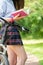 Girl wears short skirt reading book near bike
