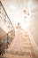 A girl in a wedding dress is walking up the stairs. beige dress. Beautiful lady in luxurious ballroom dress walking up the stairs