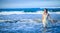 Girl in wet white dress goes in water at beach. vacation in tropical