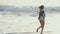 Girl wetting her hands in the water and running on the coast of the sea