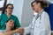 Girl with a wheelchair shaking hands with a smiling doctor and a nurse behind the chair