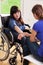 Girl on wheelchair talking with female friend