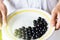 Girl in white apron keeps vintage plate with black currants