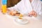 Girl in a white bathrobe eats home croissants with honey and drinks orange fresh