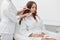 Girl in white bathrobe receiving stimulating electric facial treatment