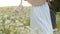 Girl in a white dress in the chamomile thickets. Wicker hat behind the girl`s back. Beautiful summer rustic shot.