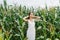 Girl in white dress with closed eyes standing in a corn field, enjoying nature