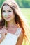 Girl in white dress, holding a dandelion blooming and smiling to you