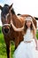 Girl in white dress leading horse.