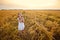 A girl in a white dress is playing in a wheat field and blowing soap bubbles. Nature in the village