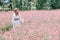 A girl in a white dress with polka dots and a hat in a flowering field of sainfoin