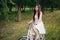 Girl in a white dress rides a bicycle through the park in the evening.