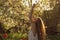 Girl in white dress sitting among flowers and fluff with threw back her head near tulips in sunset, dandelions and cherry flowers