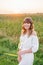 Girl in white dress with spikelets. Woman in cornfield, place for text. Spike and girl in field. Late summer and early