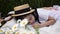 Girl in a white dress in a straw hat lie with mom in a field with daisies