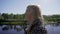 A girl with white hair and glasses is on the high embankment of the river. The camera shoots in profile. close-up face