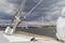 A girl in a white jacket sits on board the yacht. Ahead of the river bank bridge