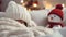 A girl in a white knitted hat covered with a blanket sits on the sofa next to a toy snowman, Christmas concept