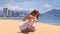 girl in white lace costume demonstrates yoga asana child\'s pose on beach