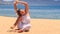 girl in white lace costume shows yoga asana leg behind head on beach