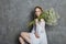 Girl white light dress and curly hair, portrait of woman with flowers at home near the window, purity and innocence. Curly blonde