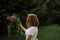 A girl in a white light dress is holding a bouquet of wild flowers over her head and spinning. Copy space, selective focus