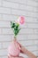 Girl with white manicure holds in hands pink vase with pink rose