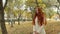 Girl in a white overcoat, with long red hair, sweeping the avenue autumn park.