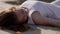 A girl in a white sarafan lies on the sand. close-up.