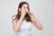 A girl in a white shirt sprays medicine in the nose for colds and colds