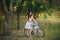 Girl in a white skirt and a vest with a bicycle and a basket full of flowers in the park in the evening