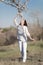 Girl in white sniffing blossoming branch of almond tree