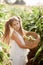 Girl in a white suit collects corn in a basket in a cornfield