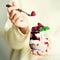 Girl in white sweater holds glass with chia milk dessert, raspberries, blueberries, mint. Healthy breakfast concept