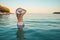 girl in white swimsuit with hat looking at sea at twilight with full moon and island in background