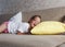 a girl in a white T-shirt is lying at home on the couch and laughing with her head on a yellow pillow.