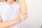 A girl in a white T-shirt massages her elbow from acute pain in the joint