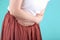 Girl in a white t-shirt and skirt holding her belly, concept of menstruation pain