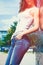 Girl in white tank shirt and blue jeans outdoor summer day  lean on tiled wall