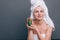 Girl with a white towel on her head with a nutritious green mask on her face and an avocado in her hands on a green background wit