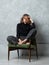 Girl with wild messy hair sitting on armchair with legs