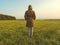 Girl in a windbreaker stands back in the field in autumn